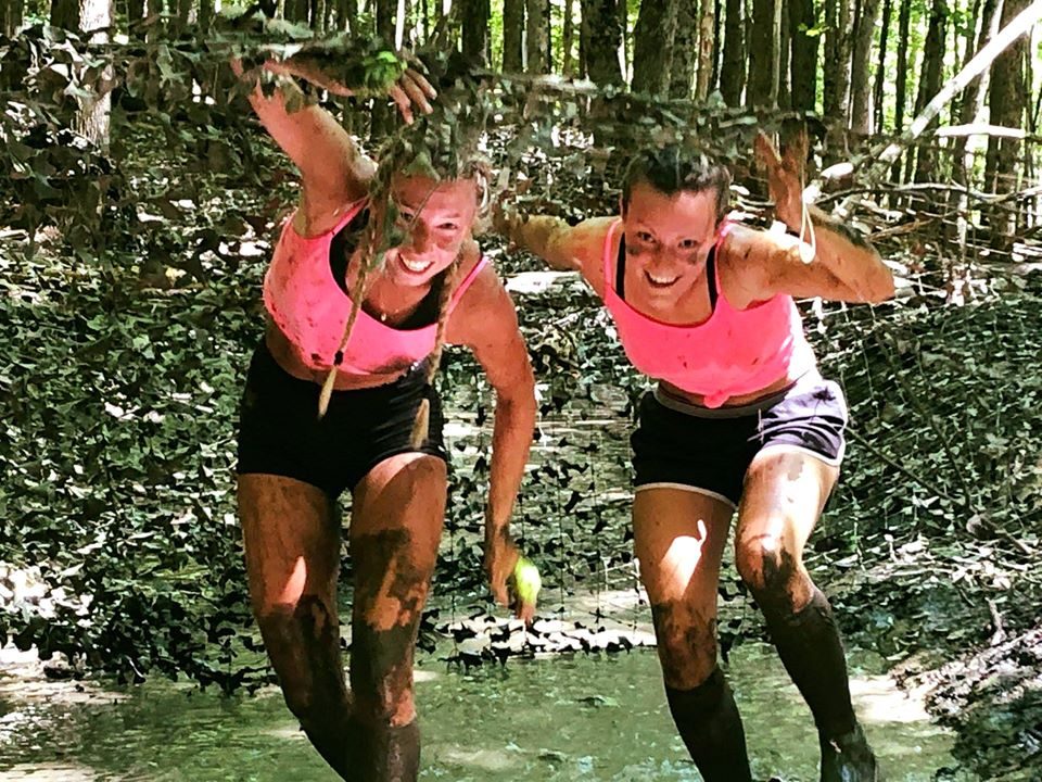 Amies couvertes de boue souriant dans la nature